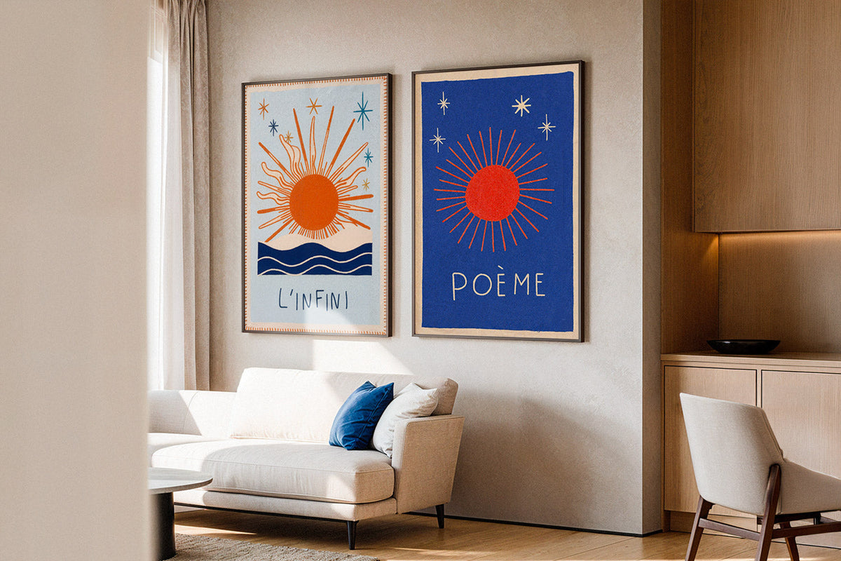Two framed posters with orange suns hung as a pair above a cream sofa in a living room