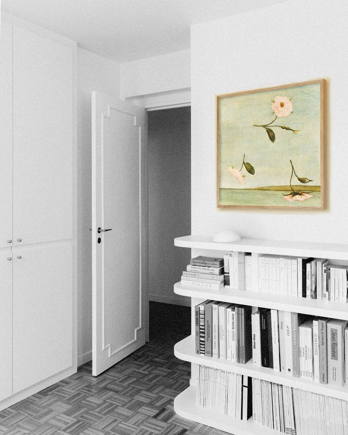 Bright bedroom corner with a white bookshelf and an oak-framed painting of pale flowers floating above a green landscape